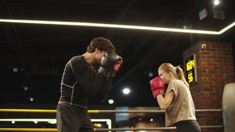 Smiling sport couple boxing at gym. Closeup attractive male and female boxers fighting on boxing ring. Sporty athletes enjoying intense training in sport club.