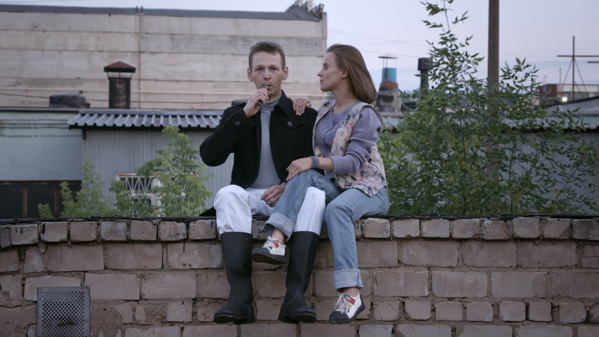 Video of couple sitting on the brick roof in summer