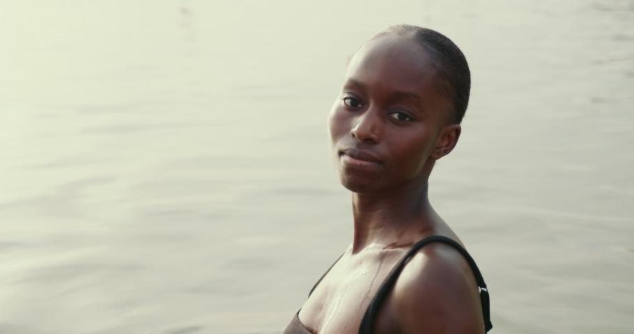 Young black girl standing in a water and looks away | Shutterstock HD Video #1083282673