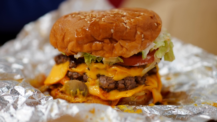 Extraordinary beef burger with cheese, lettuce and tomato in foil wrapper