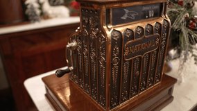 This video shows a side view of an antique cash register, next to Christmas decor on a marble countertop.