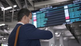 Young man traveller in face mask in airport near flight timetable. Businessman at terminal arrivals table, rear view. covid19 virus pandemic. Waiting for flight plane In terminal, travel business - Powered by Shutterstock - Get 15% off with code: PIKWIZARD15