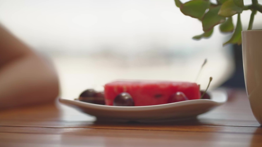 girl eating cherries and watermelon on beach close up hand