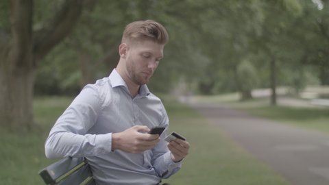 Man Sits on Bench In Park and Makes a Purchase Using His Phone - Ungraded