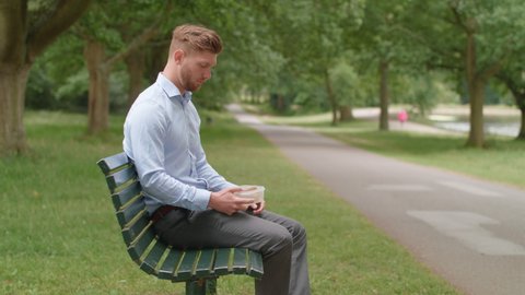 Man Sitting On Bench Eatc Lunch and Experiences Heartburn Pain