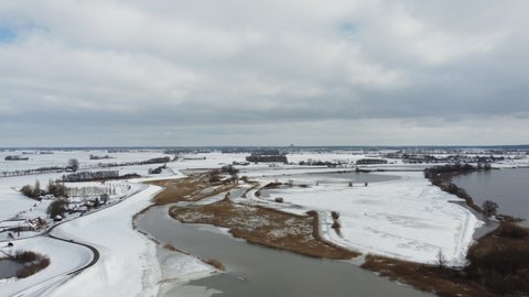 High water level on the snowy floodplains of the river IJssel near the city of Kampen in Overijssel, The Netherlands. Aerial drone point of view.