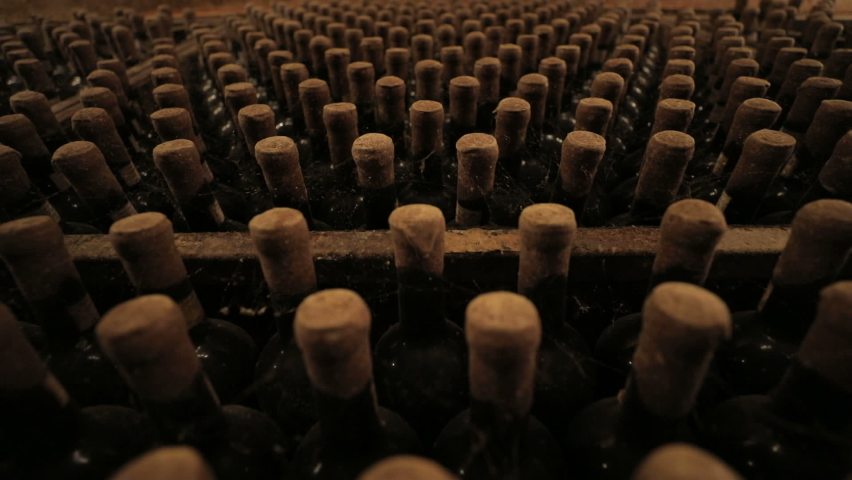 A Wine Cellar. Storage Room for Wine in Bottles and Barrels. Old wine in a dark underground vault. Wooden oak whiskey, wine, cognac, brandy or beer barrels. Bottles on wooden shelves. Royalty-Free Stock Footage #1083299026