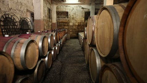 A Wine Cellar. Storage Room for Wine in Bottles and Barrels. Old wine in a dark underground vault. Wooden oak whiskey, wine, cognac, brandy or beer barrels. Bottles on wooden shelves.