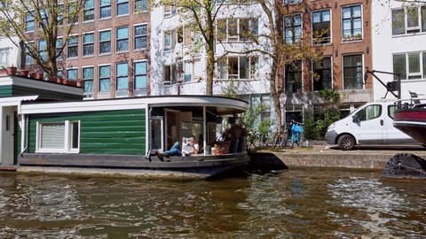 Amsterdam, Netherlands - April, 20, 2019: Houseboat on the canal of Amsterdam on a sunny day