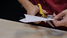 woman's hands with red nails cut a Christmas snowflake out of paper with yellow scissors. Handmade origami for decoration in happy new year - Powered by Shutterstock - Get 15% off with code: PIKWIZARD15
