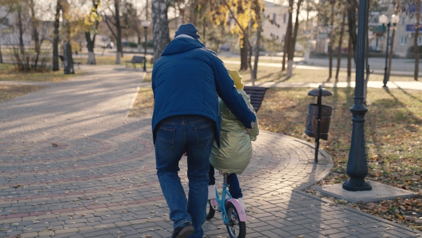 Joyful father teache little child ride two-wheeled bike happy family, childhood dream drive bicycle kid dad play merrily city park, baby spins pedals wheels, parent engaged horse riding with daughter | Shutterstock HD Video #1083302638