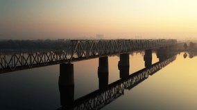 4K video of a railway bridge over the Dnieper River, Ukraine, Kyiv city. Video from the drone. Flight along the bridge. Dawn. Empty roads. Autumn. High quality 4k footage