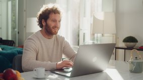 Handsome Adult Man with Ginger Curly Hair Using Laptop Computer, Sitting in Living Room in Apartment. Attractive Man is Working from Home, Online Shopping, Watching Videos or Writing Emails. - Powered by Shutterstock - Get 15% off with code: PIKWIZARD15