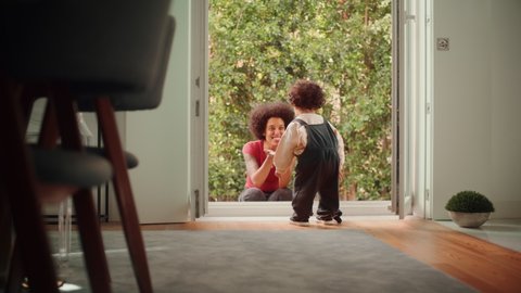Happy Mother Playing with Adorable Baby Boy, Having Fun at Modern Home Living Room. Latina Female Calling Toddler Child to Come Out to the Garden. Concept of Childhood, New Life, Parenthood.