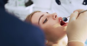 Dentistry. Dentist conducts an examination of the oral cavity with the help of a dental mirror to a young beautiful woman in a modern dental office. High quality 4k video. Shot with RED camera.