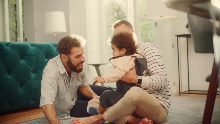 Loving LGBTQ Family Playing with Toys with Adorable Baby Boy at Home on Living Room Floor. Cheerful Gay Couple Nurturing a Child. Concept of Diverse Childhood, New Life, Parenthood. | Shutterstock HD Video #1083306832