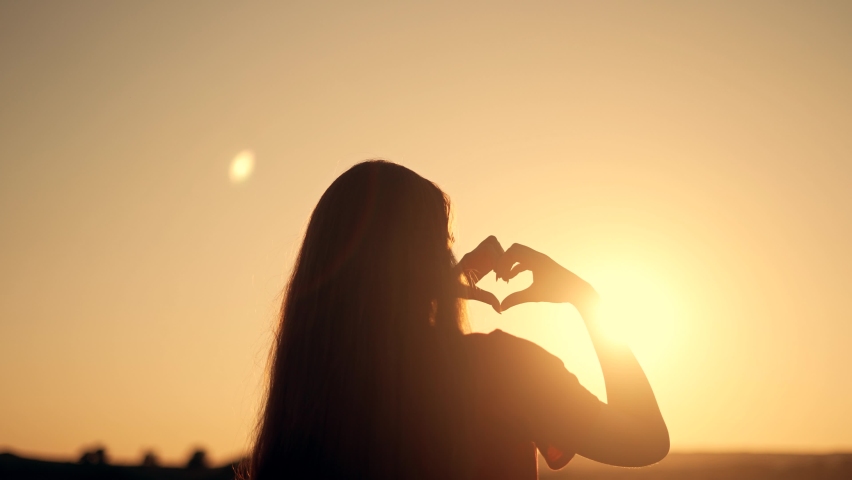 Happy girl in park at sunset. Finger-shaped heart shape. Hands of girl shape of heart. Summer dream. Happiness of freedom in a field at sunset.Sunlight between fingers.Silhouette of happy girl in park Royalty-Free Stock Footage #1083307180