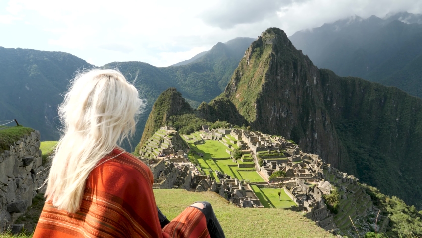 4K View of Machu Picchu. Beautiful blonde girl looking at Machu Picchu. Machu Picchu, the lost city of the Andes, located above the Sacred Valley of Cuzco, Urubamba, Peru. Famous view of Machu Picchu. Royalty-Free Stock Footage #1083308680