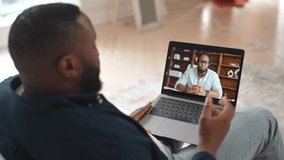 African-American man taking online language classes, online teacher on laptop screen. Two male multiracial employee talking online, discussing business tasks on the distance, friends chatting online
