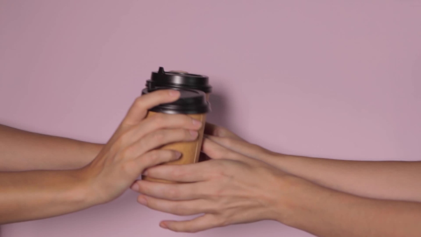 Close-up on a pink background, a woman's hand holds a paper cup with coffee in a stand. Coffee or tea to go. People hands passing one another cup of coffee, coffee delivery. | Shutterstock HD Video #1083312211