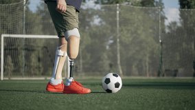 Side view unrecognizable amputee playing with soccer ball in slow motion on summer sports field. Caucasian motivated inspired sportsman with prosthetic implant training working out on stadium. - Powered by Shutterstock - Get 15% off with code: PIKWIZARD15