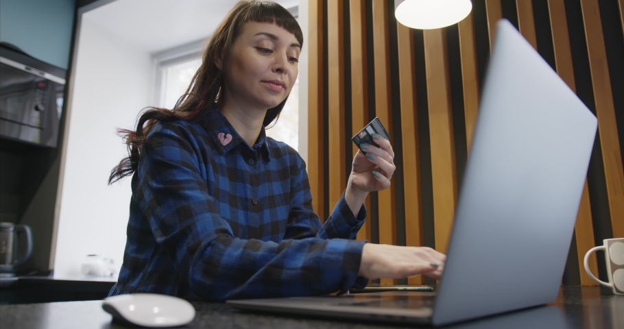 The girl enters the details of a bank plastic card for online purchases.
