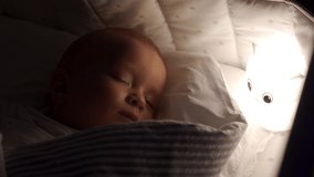 Swaddled 9 months baby boy sleeping in crib in evening in light of night lamp. Blanket is wrapped around child to calm him down and fall asleep. High quality 4k footage - Powered by Shutterstock - Get 15% off with code: PIKWIZARD15