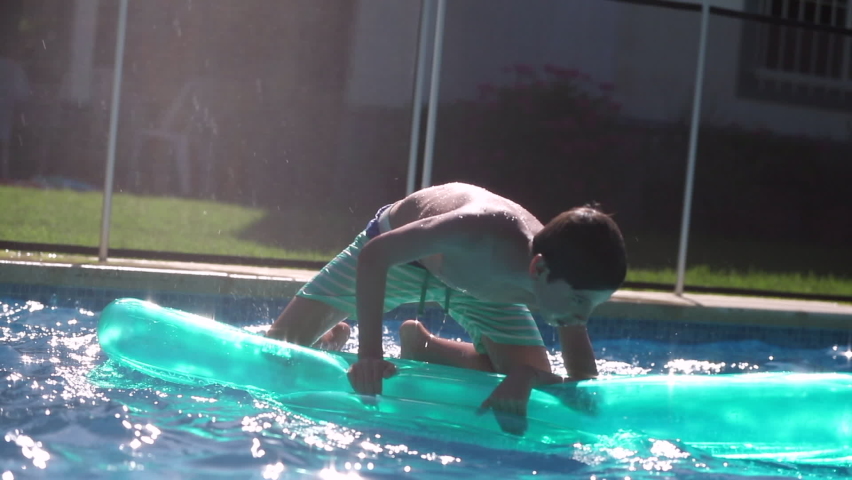 Kid standing on top of inflatable mattress keeping balance and having fun