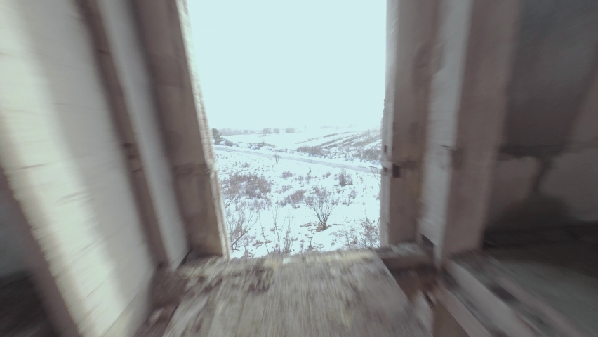 FPV drone flies maneuverable through an abandoned building. Post-apocalyptic location without people. Winter, snow, cold