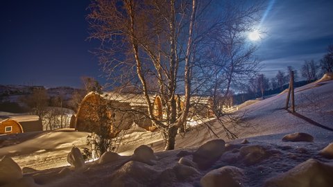 overnight at wooden cabins of Kirkenes Snowhotel in Norway. Moon glow reflecting off the frozen surface, timelapse