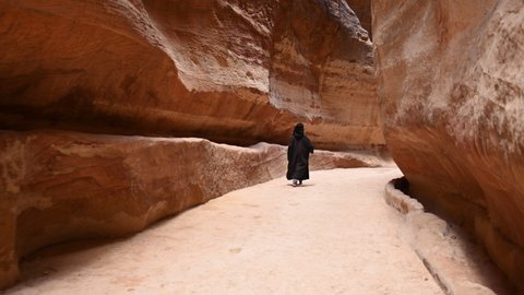 Stunning view of a person walking in The Siq. The Siq is the main entrance to the ancient Nabatean city of Petra in southern Jordan.