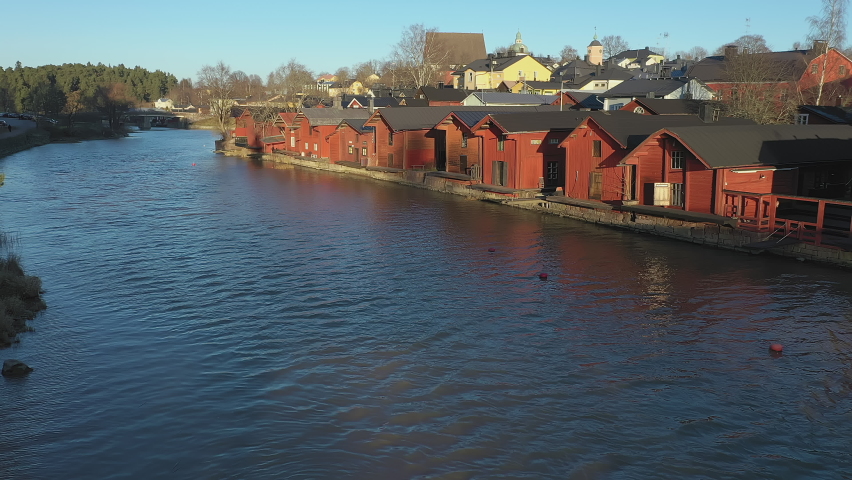 Porvoo.Finland-December 12.2020: Moving towards the red wooden riverside houses in Porvoo Finland with green forest in the background during late autumn