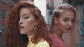 Cropped view of the two diverse girls sitting at the bike and posing to the camera. Motion camera view of two millenial girls at the urban street with graffiti walls background. Contemporary life - Powered by Shutterstock - Get 15% off with code: PIKWIZARD15