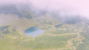 In the mountains of the Carpathians, Ukraine, in a foggy valley of fog, video by a drone copter, the famous Lake Vorozheska, on Mount Svidovets. Sheep are grazed here in summer