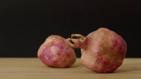 Red pomegranate on a wooden board on a black background, natural and vitamin red fruits. Slow motion, filmed on high speed cinema camera, 8K downscale, 4K.
