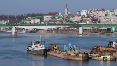 Belgrade, Serbia - November 25, 2021: Moored Barges at River Sava Old Arch Bridge Sunny autumn Day.