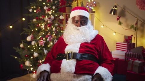 Happy Santa Claus portrait. Smiling african american man in christmas costume of santa close-up, looking in camera. Cheerful st Nicholas posing in living room. New year time concept.