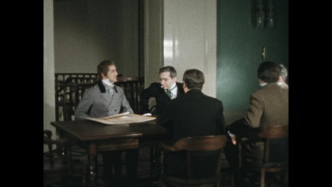 1950s: Men sit at table and talk. Man stands and shows poster. Hand holds chalkboard shooting slate. Painting of man and children.