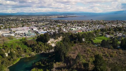 Taupo, town and lake aerial scenic cityscape tilt down to Waikato river, New Zealand