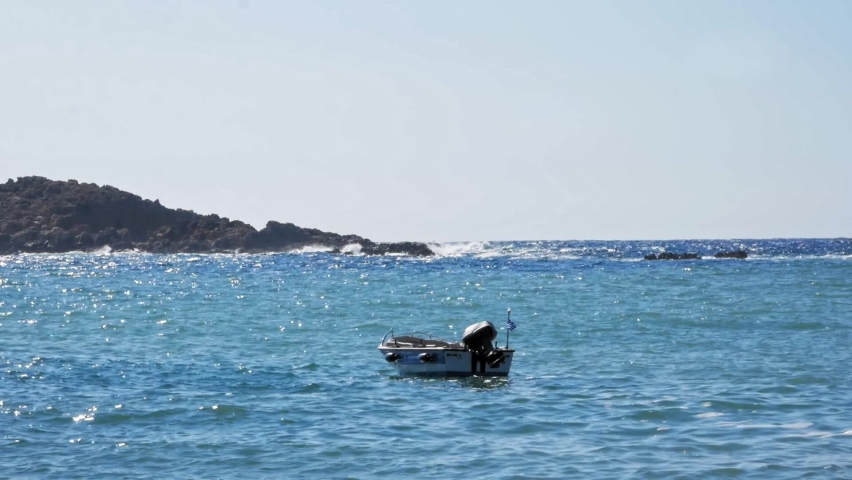 Motorboat floating on clear blue sea in Jerusalem beach in Greece - static shot