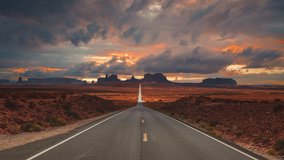 Scenic and cinematic golden red cloud sunset time-lapse at the iconic Forrest Gump spot road at the Monument Valley tea kettle rocks landmarks in Utah, Arizona, America USA. Cinemagraph seamless video