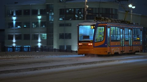 Winter, nighttime cityscape modern tram rides across the bridge in winter
