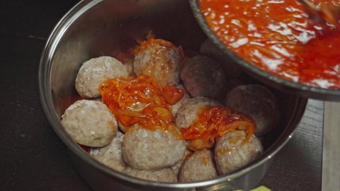 Meatballs in pan are poured with red tomato sauce