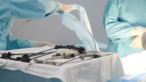 Preparation for surgical laparoscopic surgery in clinic. Nurse in operating room passing sterile laparoscopic instrument. health and medicine. Hands of surgeon picking up instrument for laparoscopic