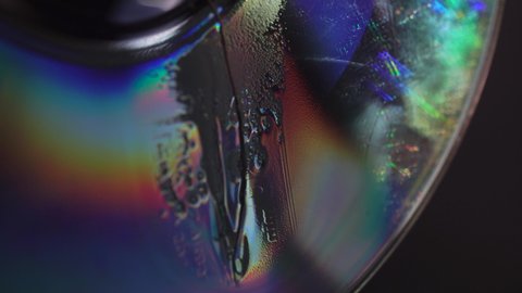 Burning an old CD disc. The concept for the end of an era. Macro 4k video of an old CD disc being destroyed. Detailed bubbles background.