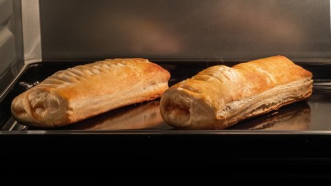 Timelapse - two puff pastry buns with apple jam baking and rising on tray in electric oven in kitchen at home. Homemade bakery, food, cooking, pastry and time lapse concept