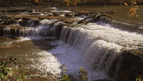 This epic slow motion video shows a rushing waterfall landscape surrounded by falling autumn leaves at Cataract Falls in Indiana.