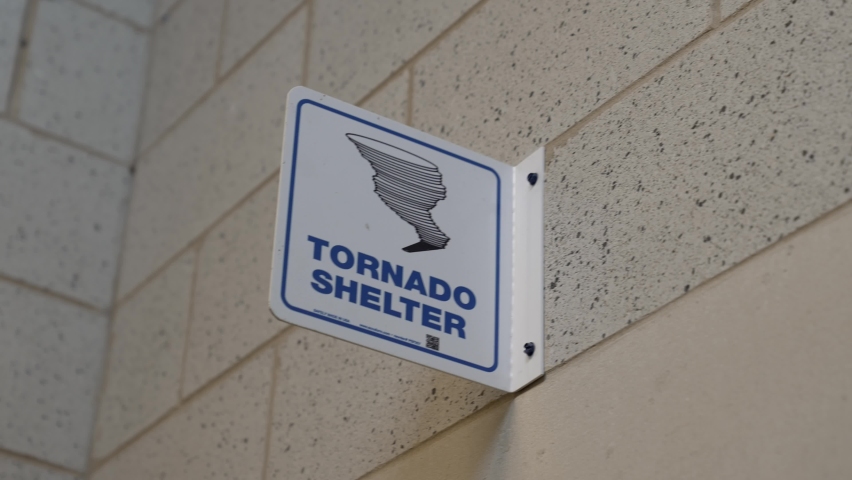This panning video shows a tornado shelter sign posted on a wall.
