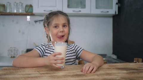 Little girl drinks milk for breakfast. Organic drink. Girl with glass of milk. Organic healthy product. Child with a glass of milk. Child drinks milk for breakfast. Organic healthy products concept.