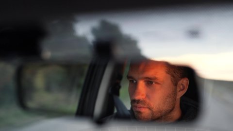 Young man inside car. Happy positive caucasian man driving car fast. Blurred background. Sunrise or sunset outside the window